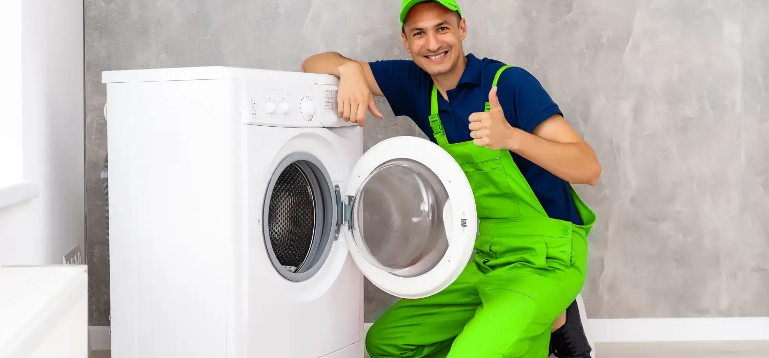 Washing machine repair man sitting beside the washer after fixing in Dubai